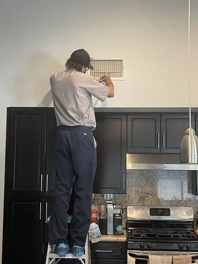 Technician inspecting an air vent during HVAC service in Siler City